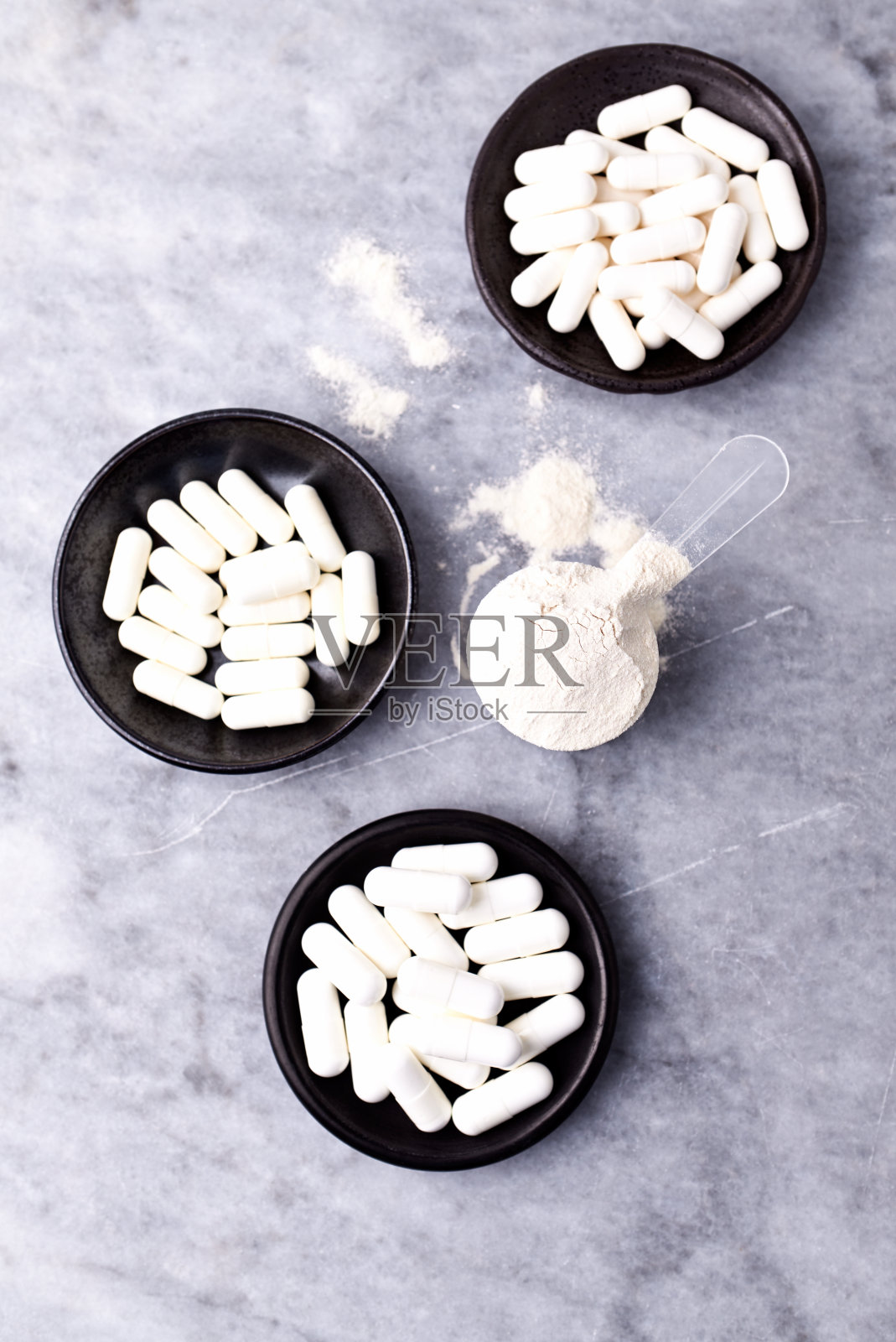 乳清蛋白,水解膠原I型,l -脯氨酸和l -賴氨酸膠囊勺。補充膠原蛋白的生產。明亮的石頭背景。直接上圖。副本的空間。